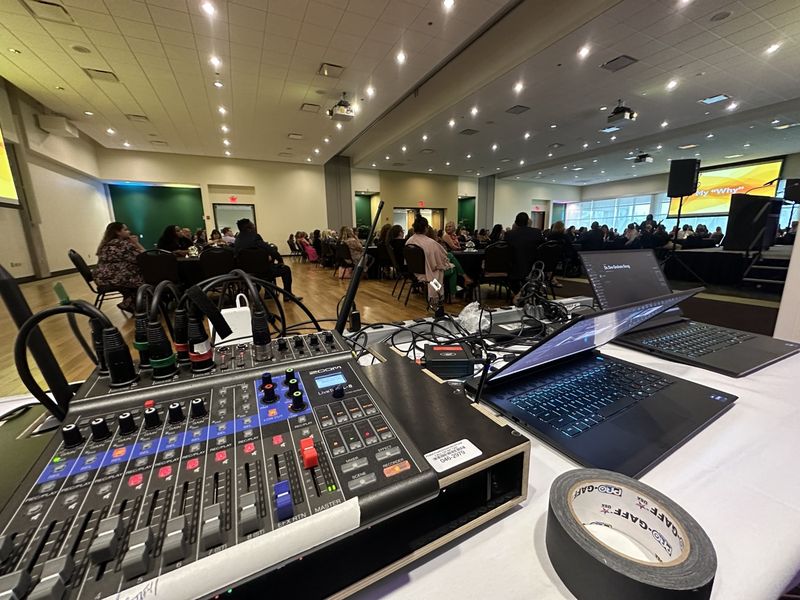 Small mixer and laptops at the back of a banquet room during a corporate luncheon