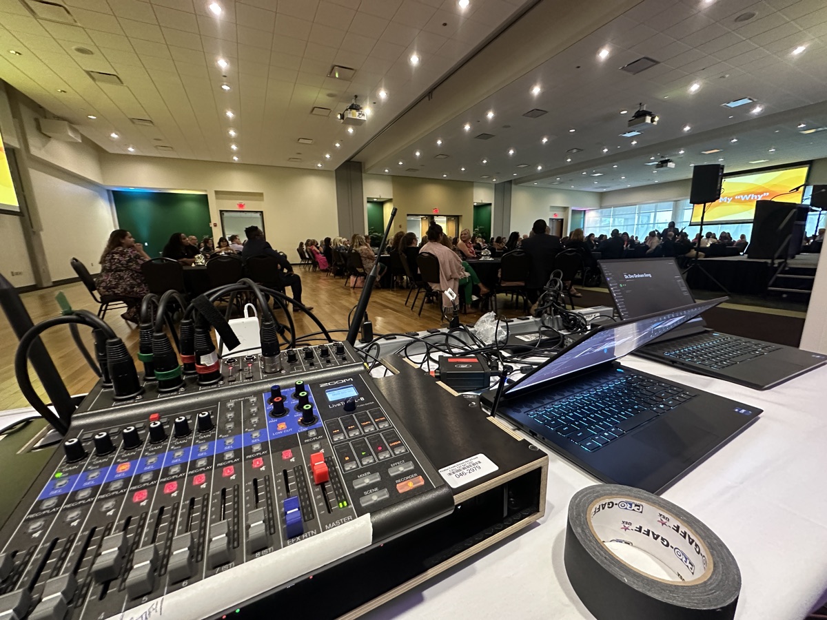 Small mixer and laptops at the back of a banquet room during a corporate luncheon