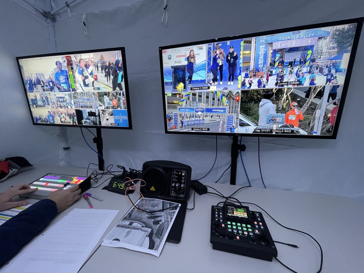 Two multiview monitors and a video switcher under a tent at a live event