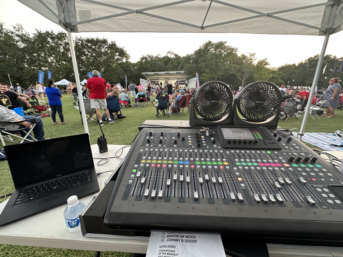 Digital mixing console under a tent at an outdoor community concert