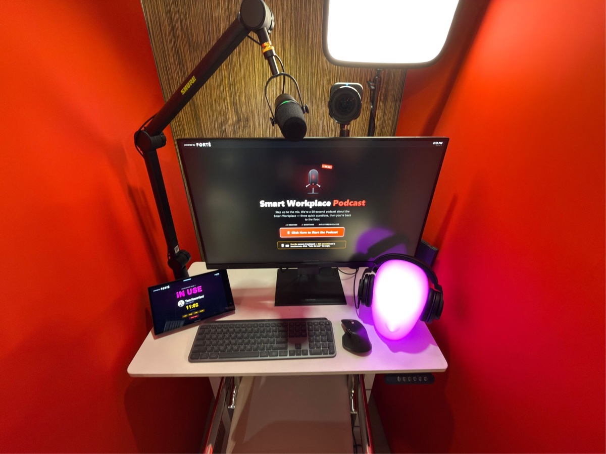 Podcast recording desk with a Shure microphone on a boom arm, monitor, and key light
