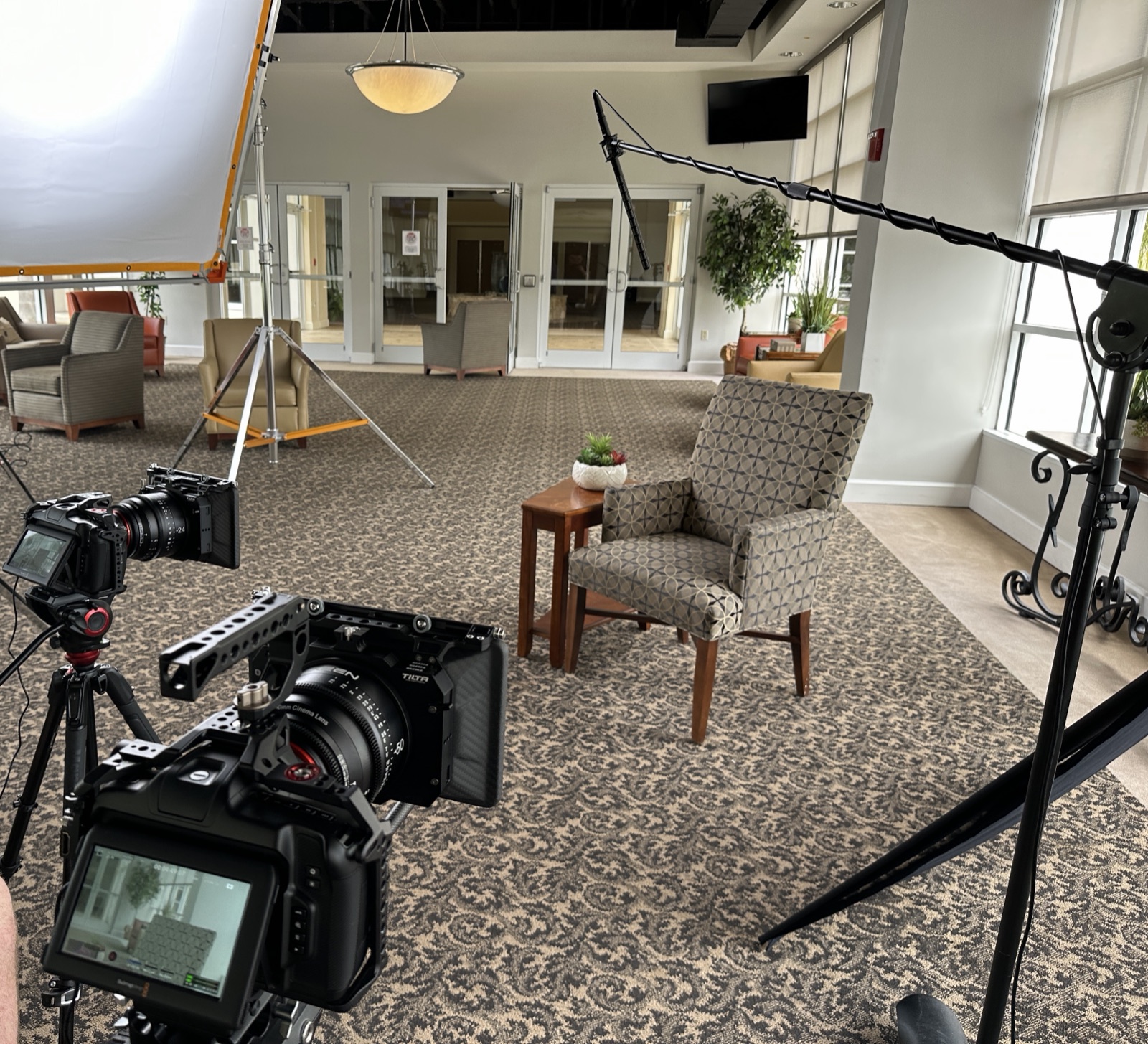 Interview setup with two cinema cameras, softbox, and boom microphone in a lobby