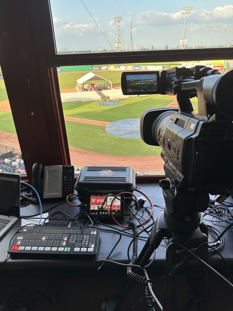 Broadcast camera and switcher in a press box overlooking a ballpark