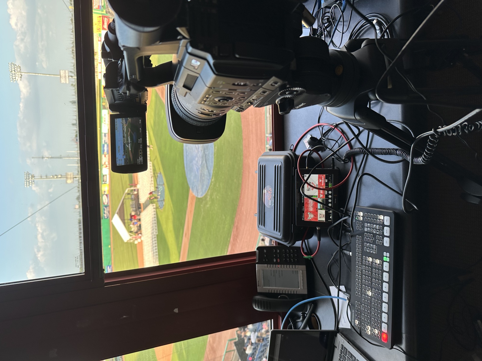 Broadcast camera and switcher in a press box overlooking a ballpark